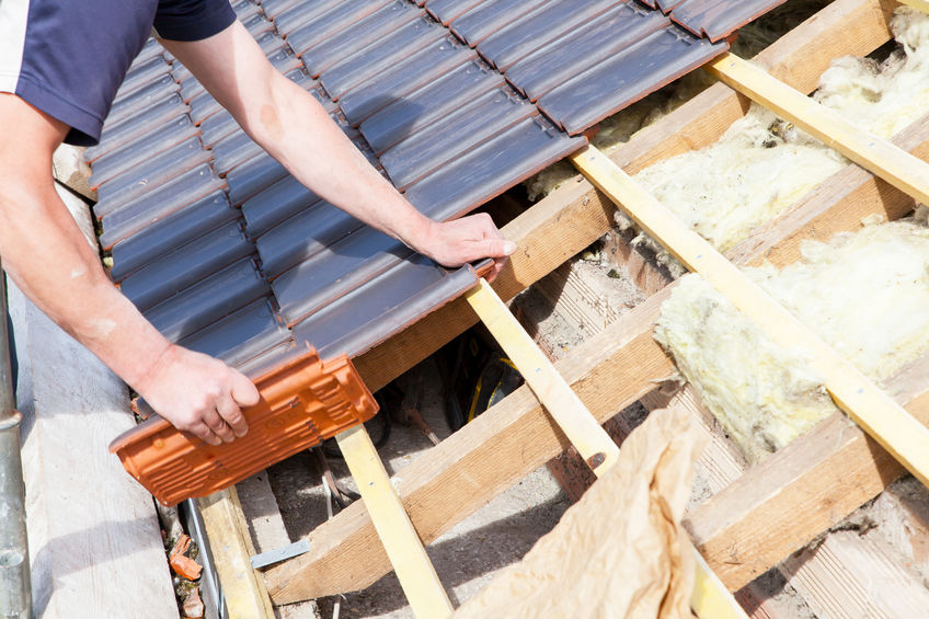 a roofer laying tile on the roof