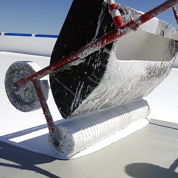 silicone roof coating being applied through a large roller machine